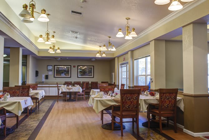 An elegant dining room with neatly arranged tables and chairs, enhanced by warm lighting.