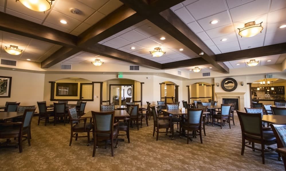 A spacious dining room with arranged tables and chairs, warmly lit by ceiling lights.