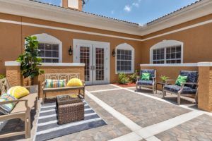 A sunny courtyard featuring outdoor furniture and brick flooring, perfect for relaxation.