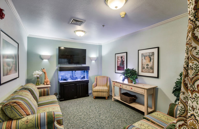 A cozy waiting room featuring an aquarium, comfortable seating, and a television.