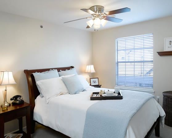A cozy bedroom with a neatly made bed and a ceiling fan.