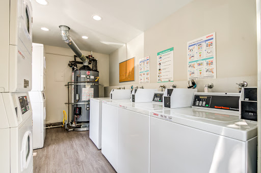 A modern laundry room featuring several washing machines and a dryer, designed for efficient use of space.