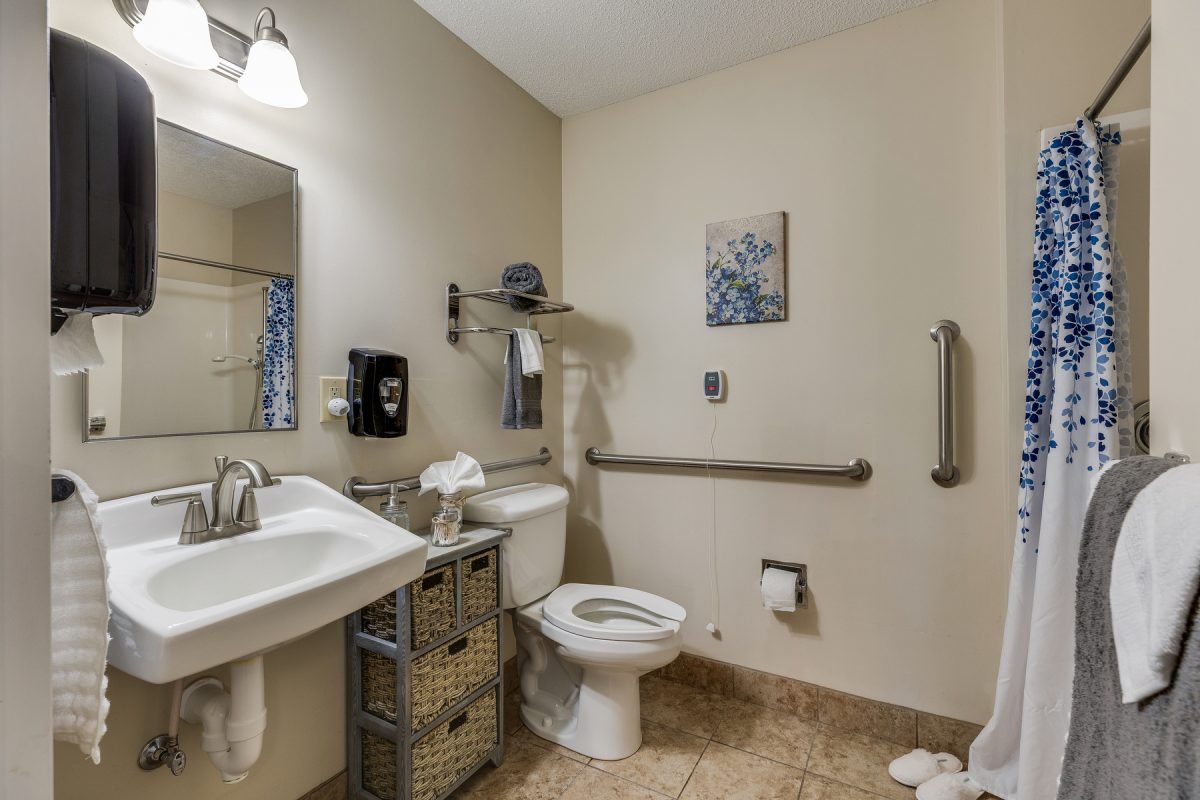 A well-organized bathroom with a sink, toilet, mirror, and storage baskets.