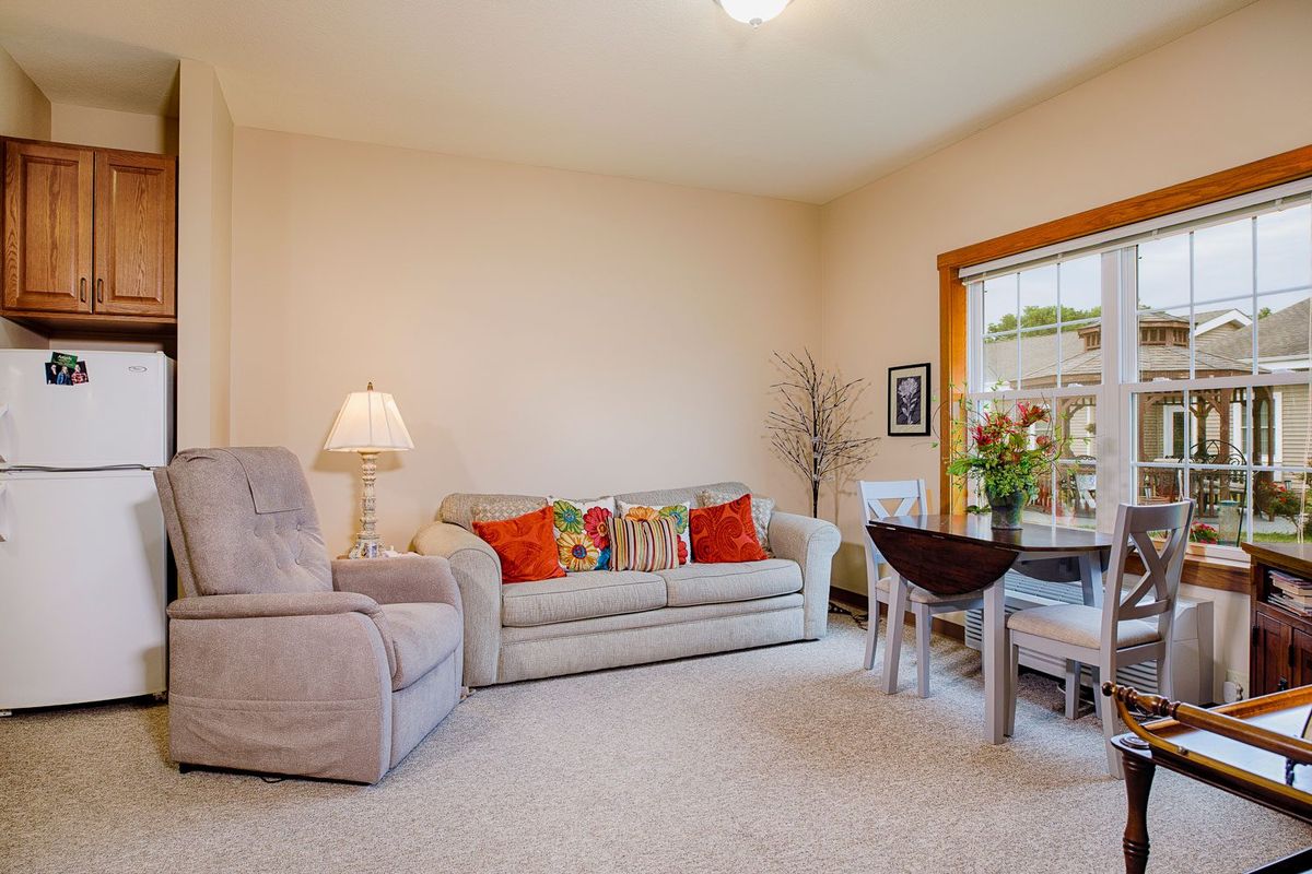 A cozy living room with a sofa, armchair, and a small coffee table by the window.