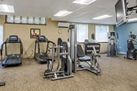 A gym room equipped with various fitness machines, including a treadmill and weightlifting equipment.