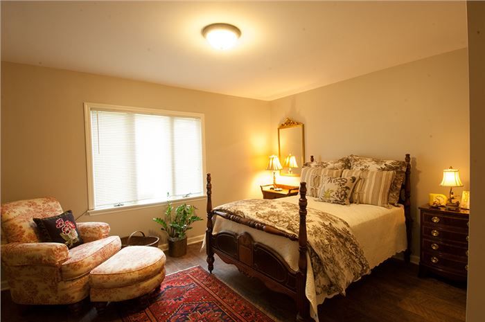 A cozy, traditionally decorated bedroom with a four-poster bed, warm lighting, and comfortable seating.