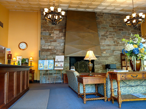 A cozy lobby with a stone wall and elegant lighting, featuring comfortable seating and a reception desk.