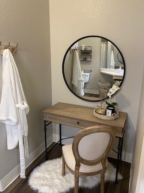 A modern vanity setup with a round mirror and wooden dressing table.