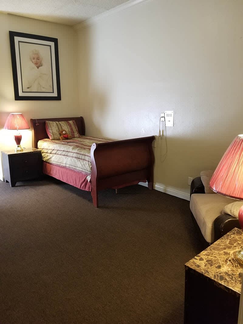 A cozy bedroom with a single bed, side table, and lamps.