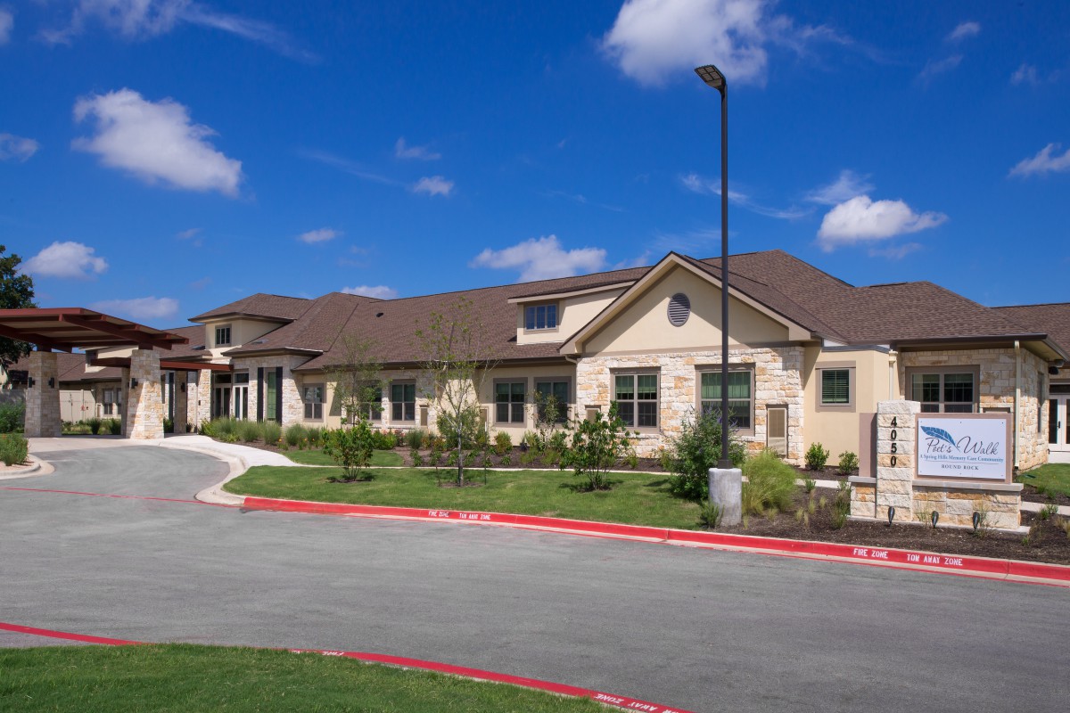A modern residential building with well-maintained landscaping under a clear blue sky.