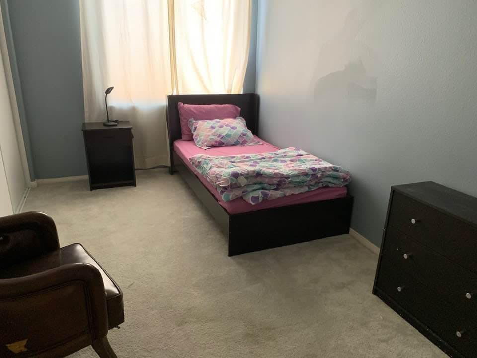 A simple bedroom with a single bed, nightstand, and dresser.