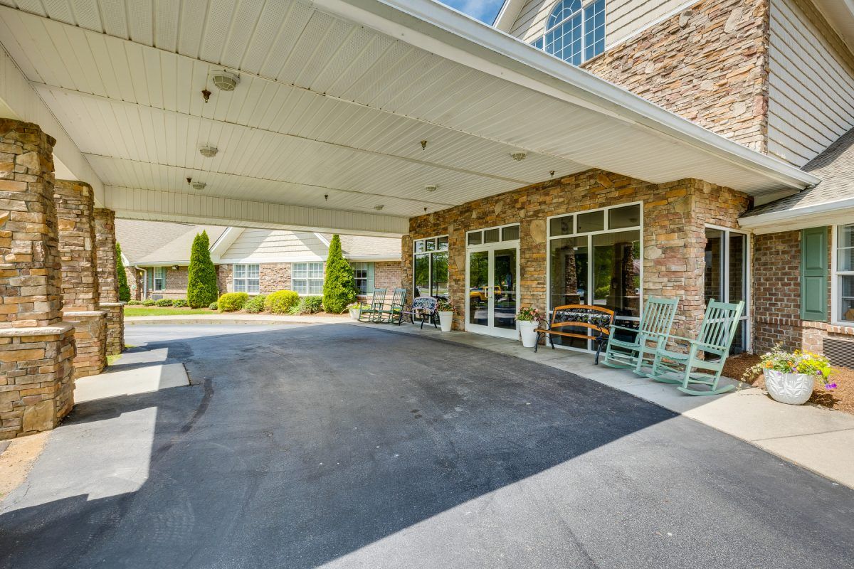 The image shows the exterior entrance of a building with a covered driveway and brick facade.