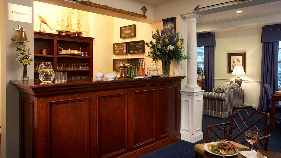 A hotel's reception desk with a flower arrangement and an adjacent waiting area.
