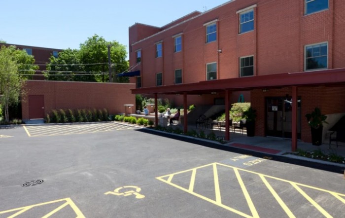A brick building with a parking lot featuring accessible parking spaces on a sunny day.