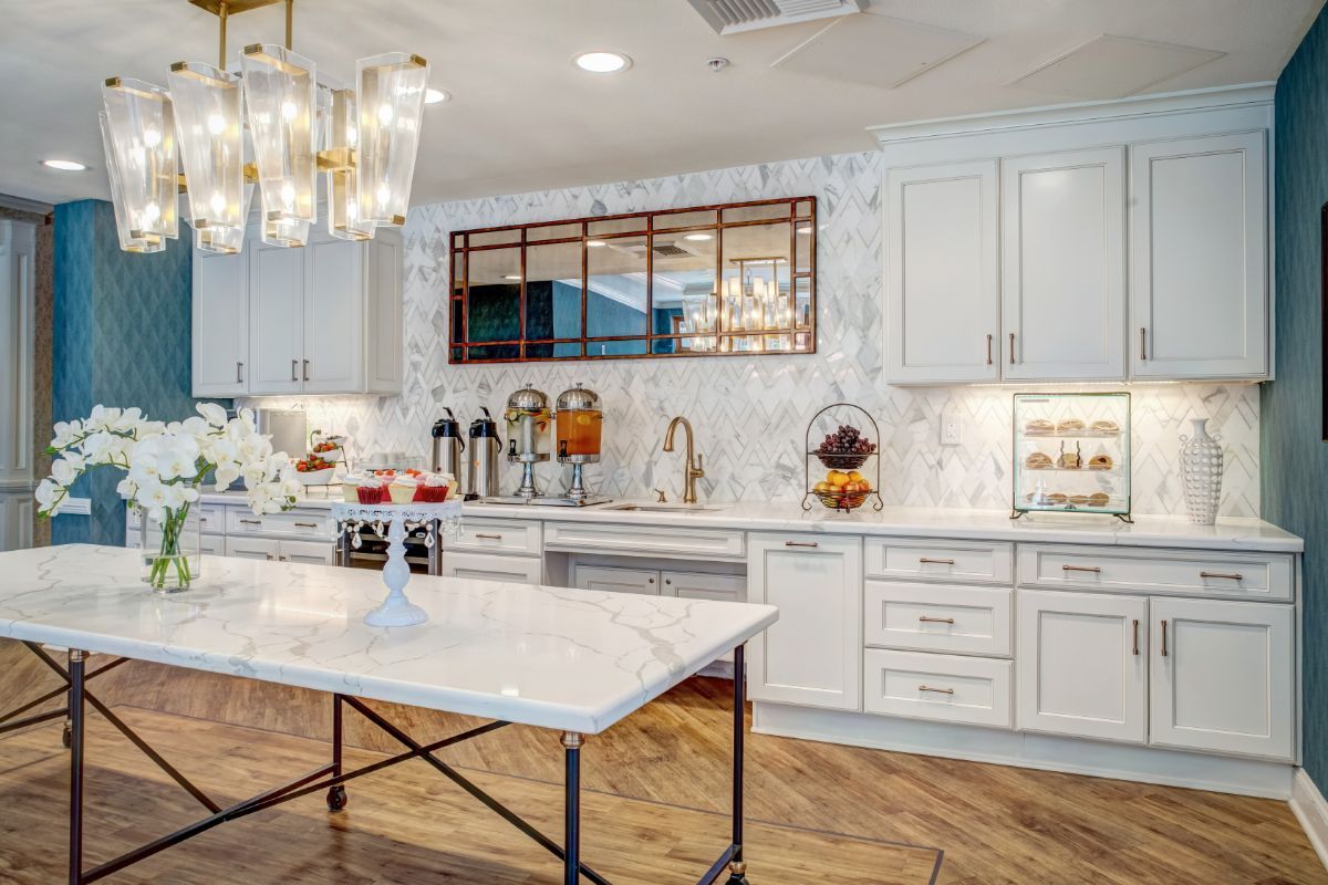 A stylish modern kitchen with marble countertops and elegant chandeliers.