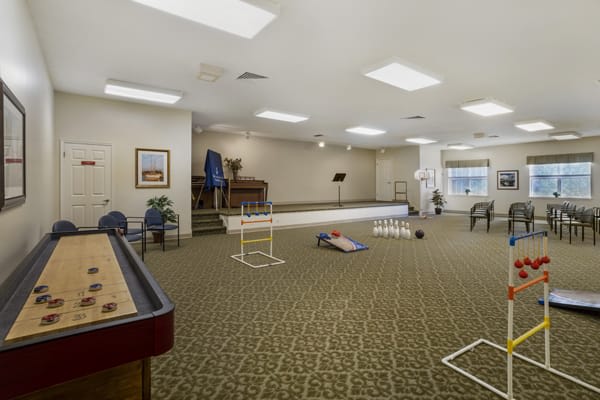 A spacious indoor recreation room featuring a shuffleboard table and various games.