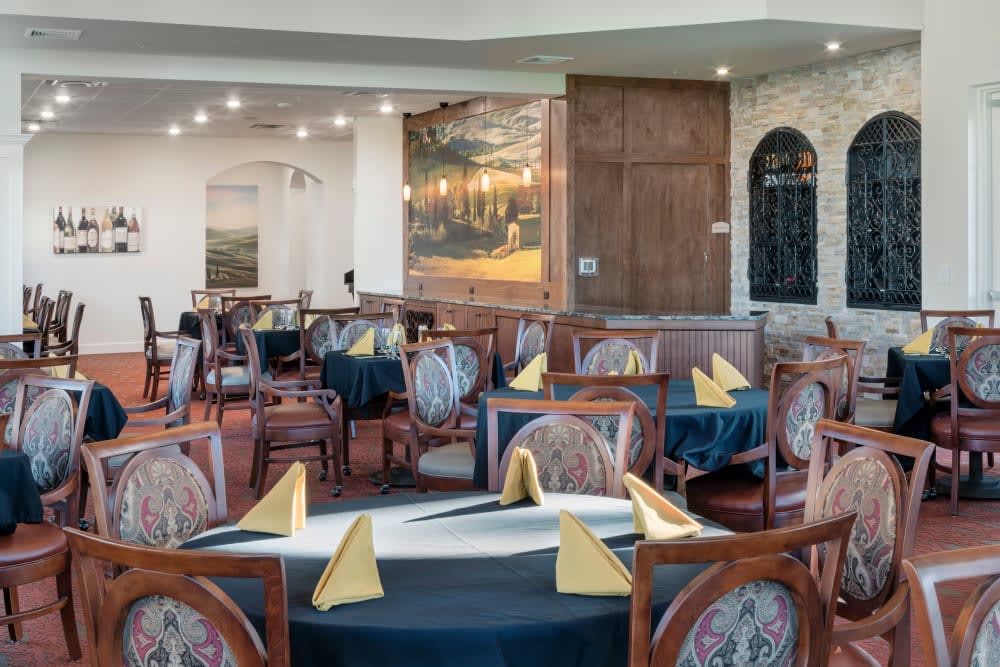 An elegantly set dining room in a restaurant with neatly arranged tables and chairs, featuring folded napkins and tasteful decor.