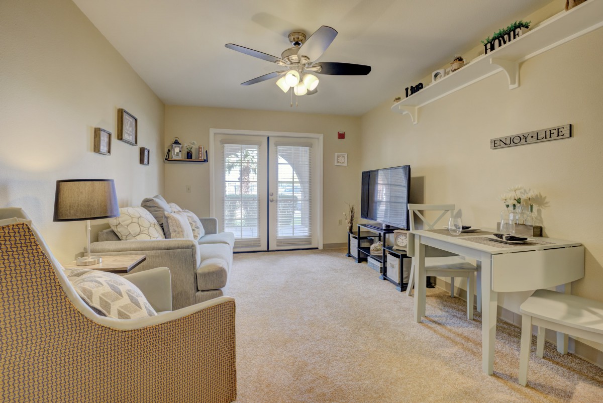 A cozy living room with comfortable seating, a ceiling fan, and a television.