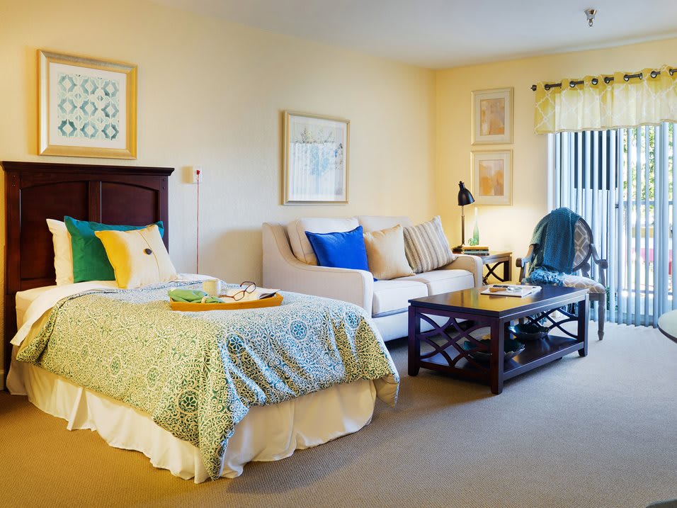 A cozy bedroom with a bed and a small living area featuring a sofa and coffee table.