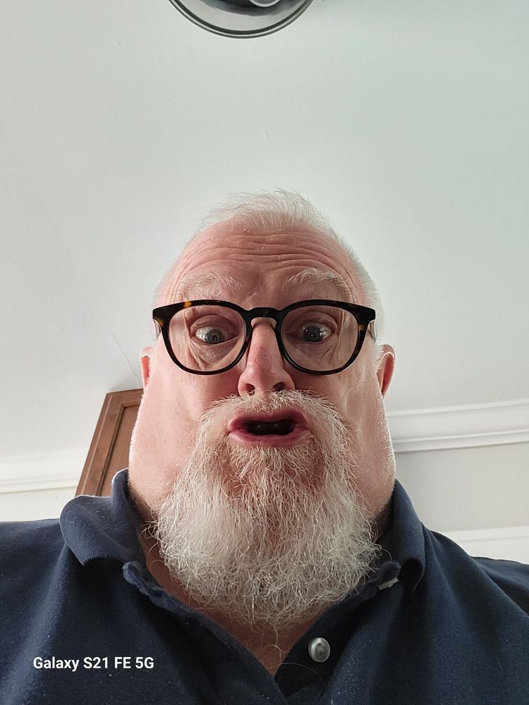A man with a beard and glasses making a surprised face.