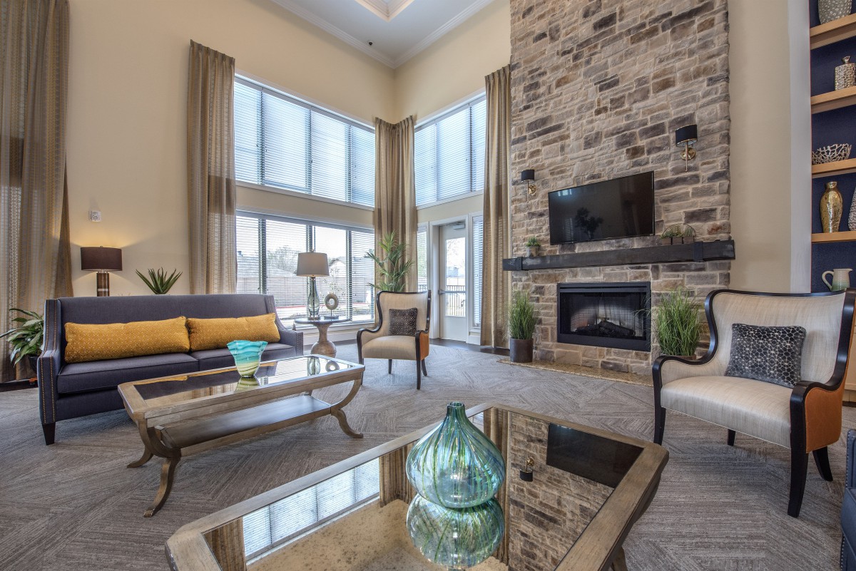 A modern living room with a stone fireplace and large windows, featuring stylish furniture and decor.