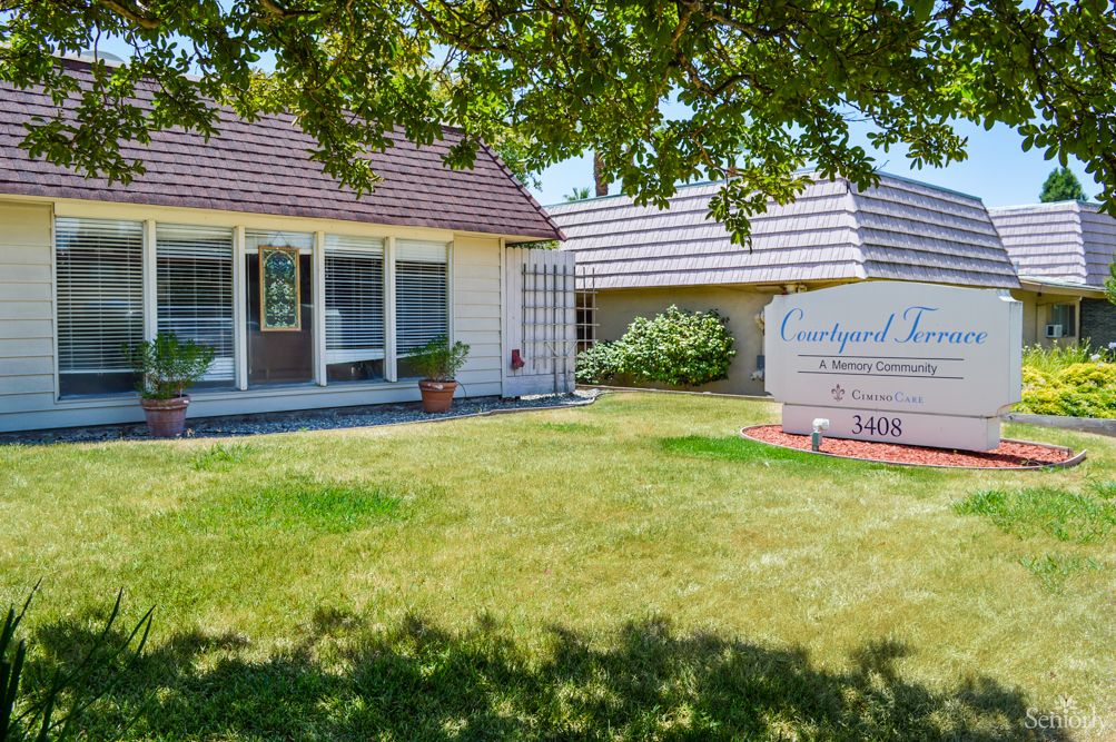 A suburban house with a well-maintained lawn and a sign in the front yard.