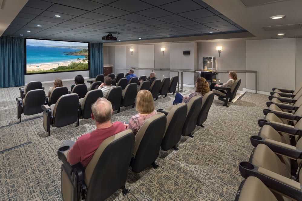 An audience seated in a theater watching a movie on the big screen.