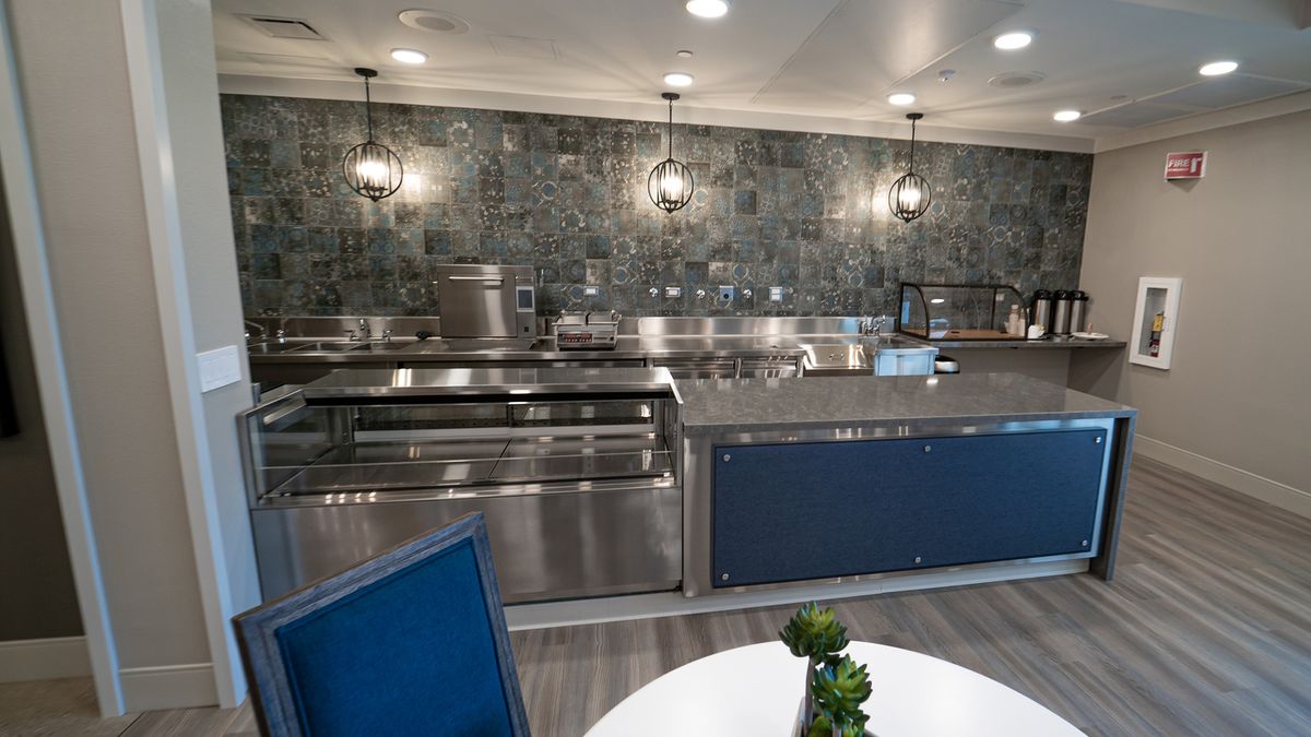 A modern commercial kitchen with stainless steel appliances and decorative lighting.