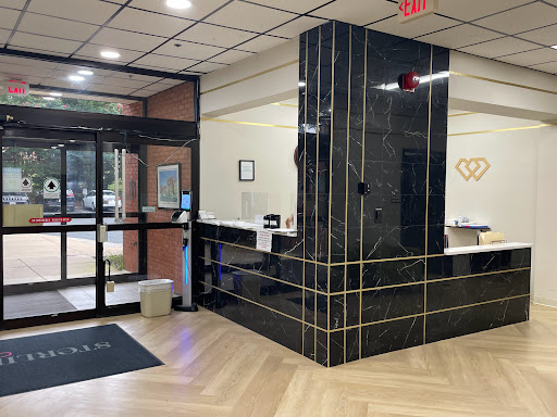A modern reception area featuring a sleek black marble counter and warm wooden flooring, welcoming visitors into the lobby.
