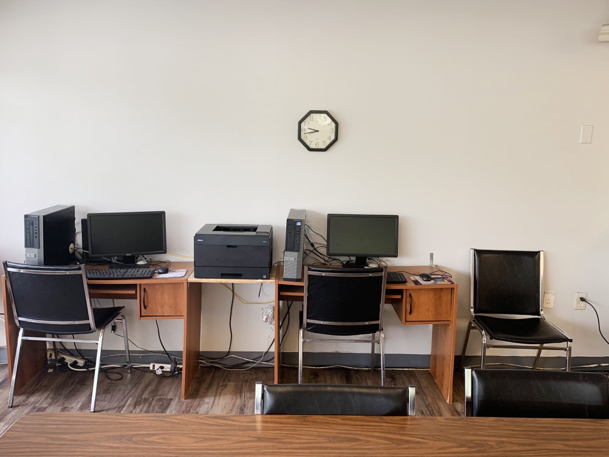 A quiet office space with several workstations equipped with computers and a printer.