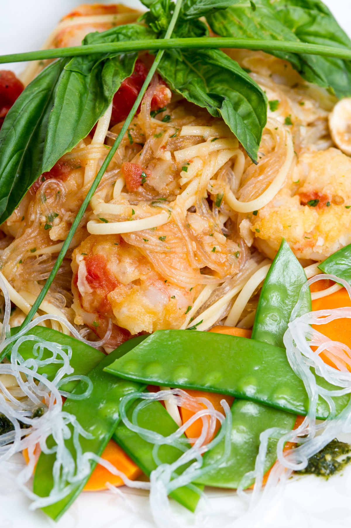 A delicious dish featuring shrimp pasta garnished with fresh basil and snow peas.