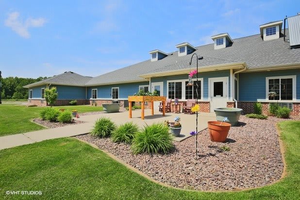 A well-maintained outdoor area with a patio, garden landscaping, and a modern building in the background.