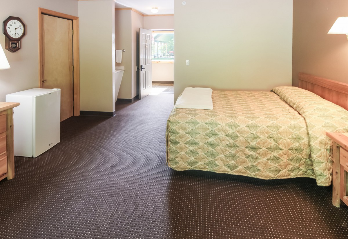 A spacious hotel room featuring a bed and simple furnishings.