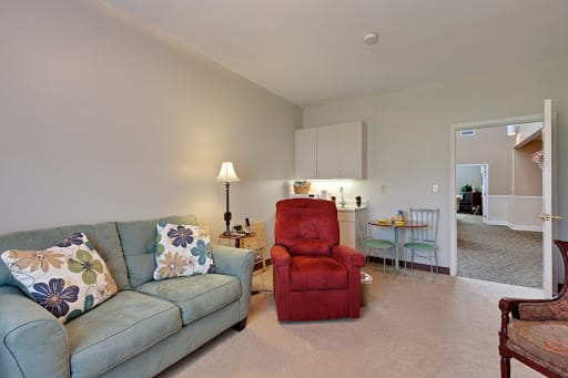A cozy living room with a sofa, armchair, and lamp.