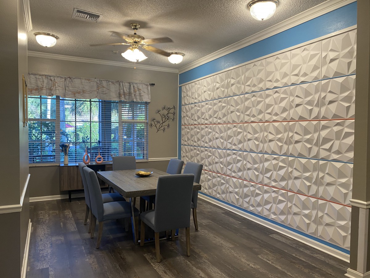 A modern dining room featuring a quilted accent wall and contemporary furnishings.