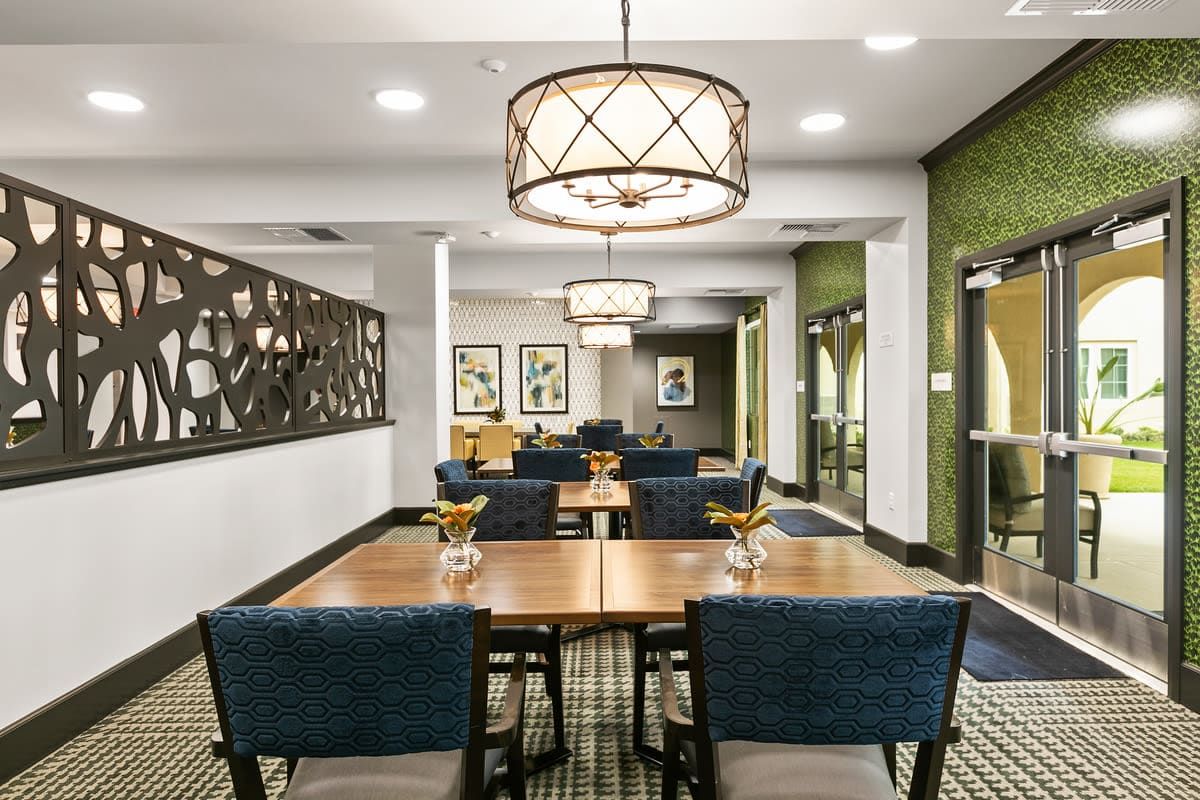 A modern dining area with stylish chandeliers, artwork, and neatly arranged tables and chairs.