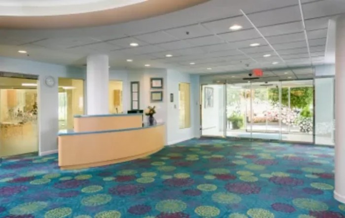 A modern lobby with a reception desk and colorful carpet.
