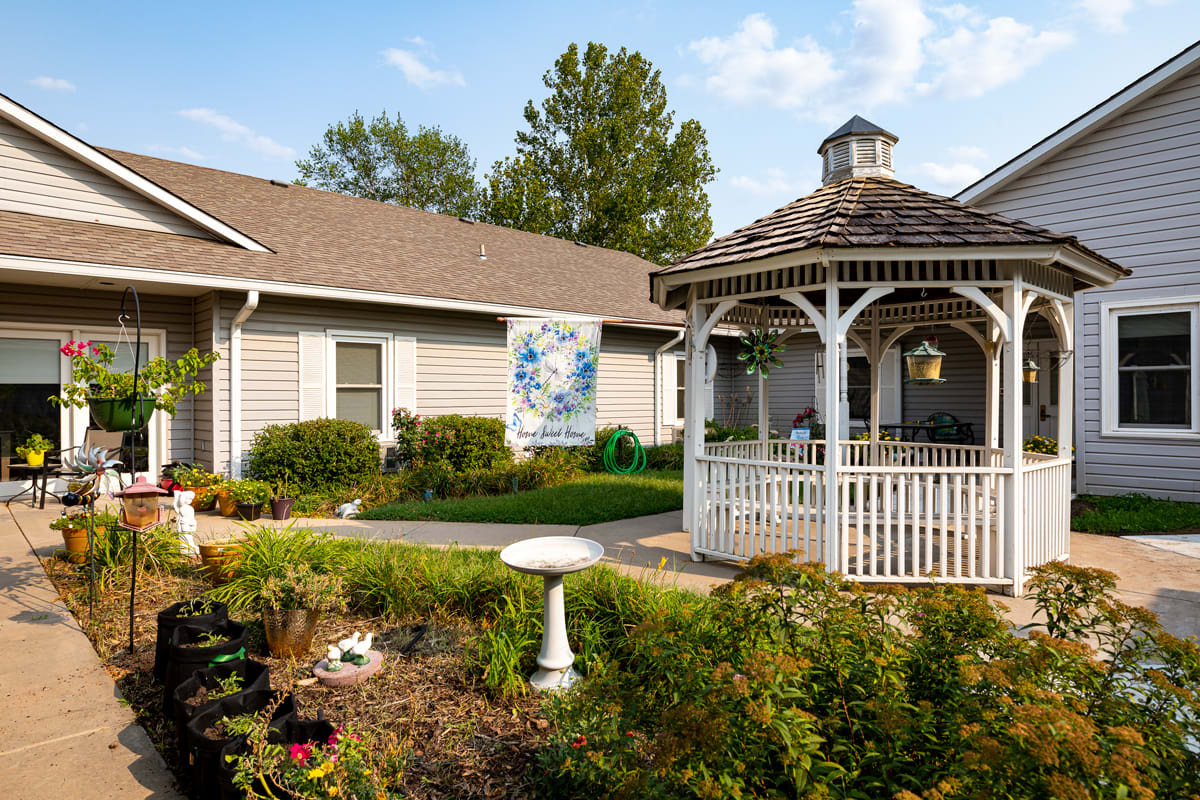 A charming gazebo surrounded by a well-maintained garden in front of a building.