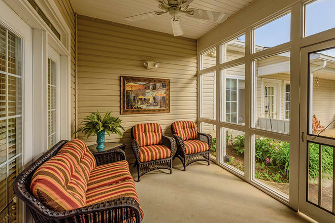 A cozy enclosed porch with comfortable seating and decorative elements.