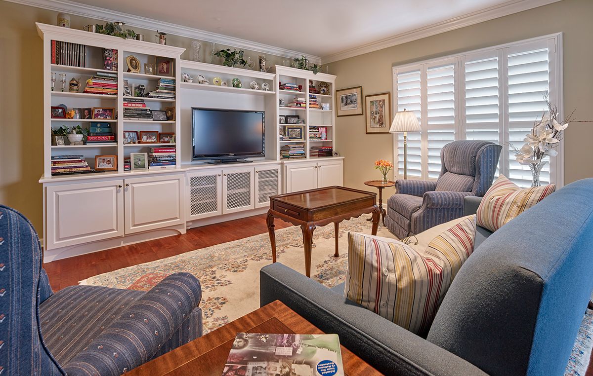 A cozy living room with armchairs, bookshelves, and a television.