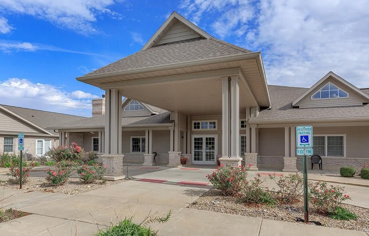 A residential building with a prominent entrance and columns under a clear blue sky.