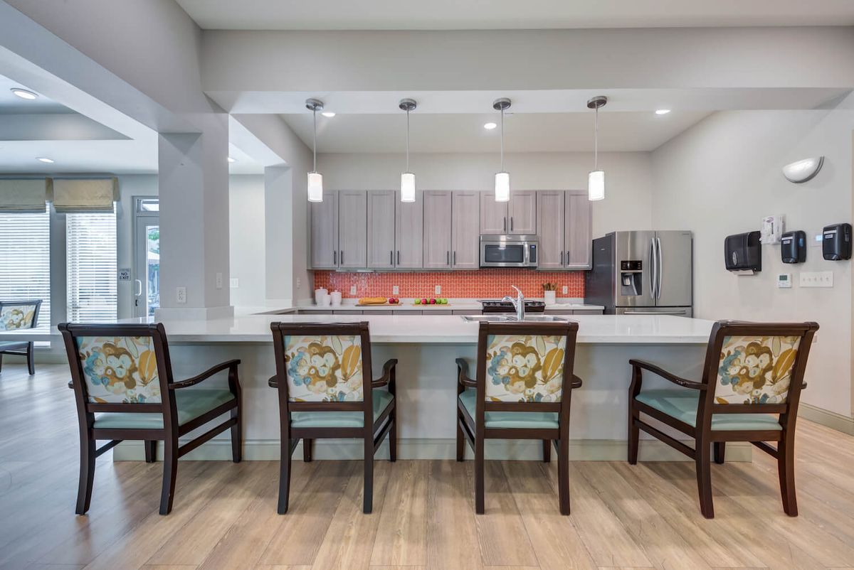 A modern kitchen interior with a sleek design, featuring a central counter with chairs and contemporary appliances.
