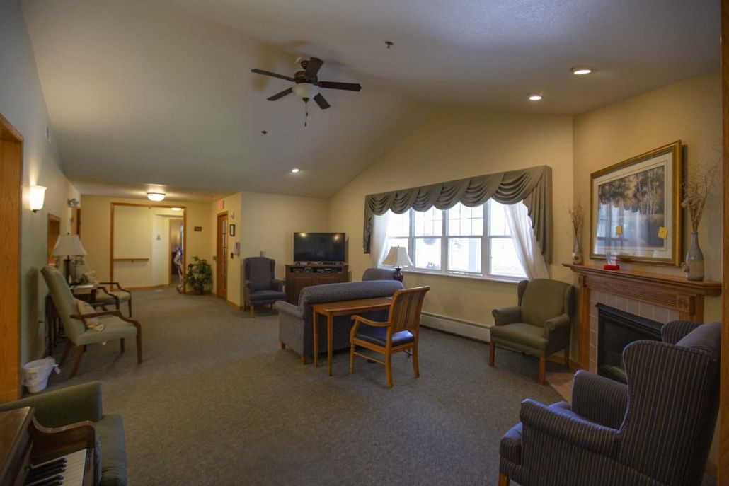 A cozy living room with a seating area, television, and ceiling fan.