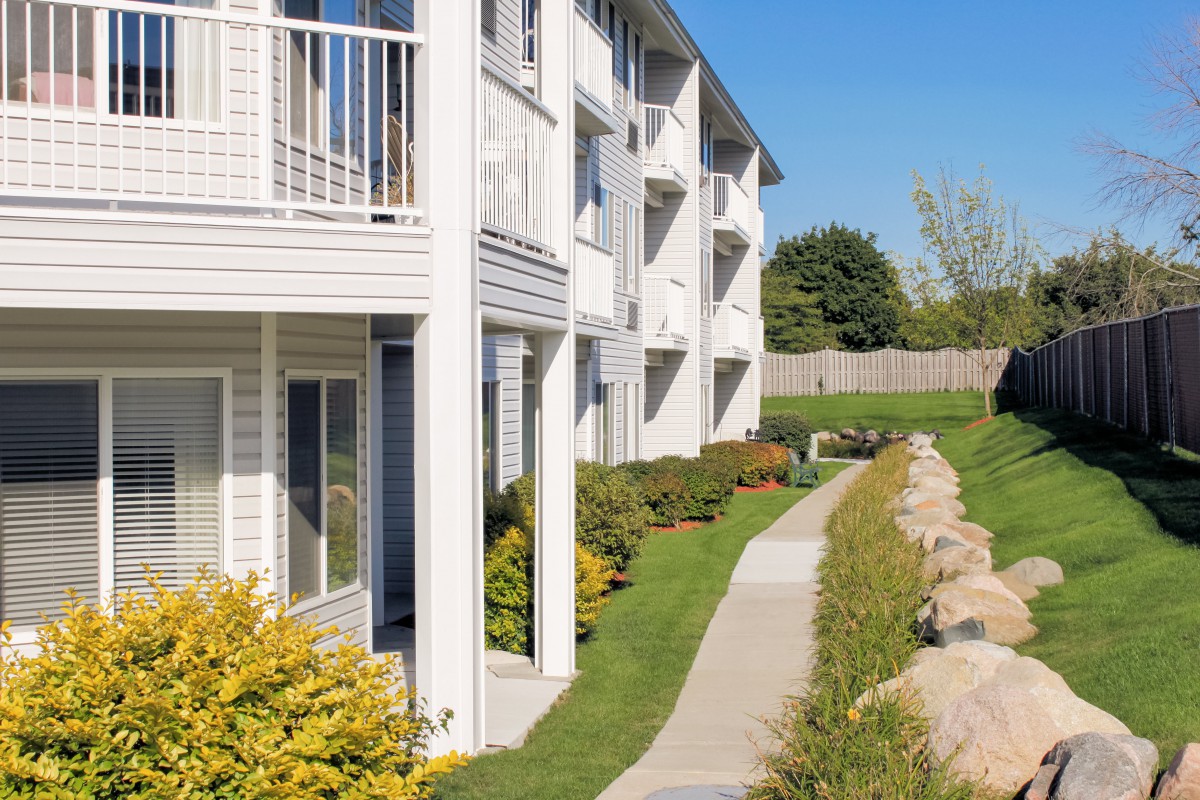 A sunny day at a residential apartment complex with well-maintained landscaping and a walking path.