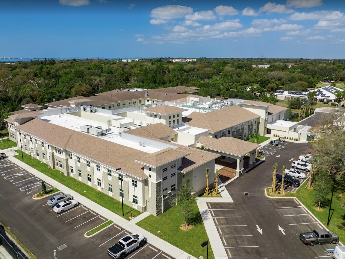 Aerial view of a modern building with a parking lot and surrounding greenery.