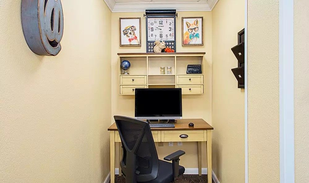 A compact home office setup featuring a desk, computer, and decorative wall art.