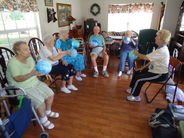 A group of seniors participating in a seated ball game indoors.