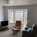 A cozy living room with a recliner, TV, and large windows offering a scenic view.