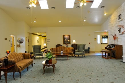 A spacious living room with various seating arrangements and warm lighting.