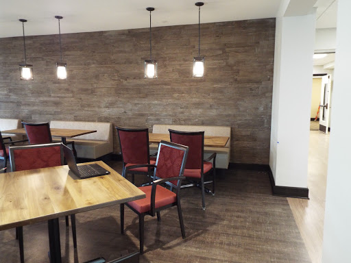A cozy dining area featuring modern chairs and tables, with warm lighting against a textured wall.